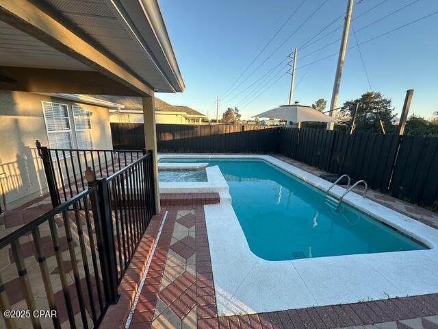 view of swimming pool with a fenced backyard and a pool with connected hot tub