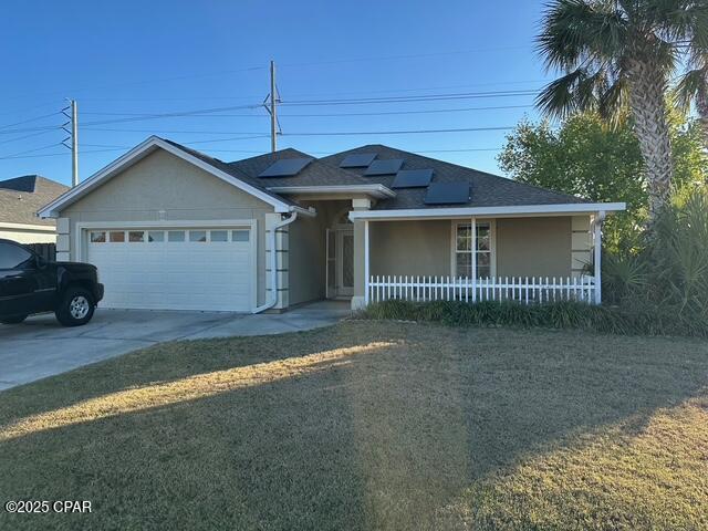 ranch-style house with concrete driveway, stucco siding, a front yard, and a garage