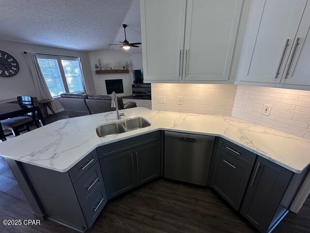 kitchen featuring ceiling fan, a sink, a peninsula, dark wood-style floors, and dishwashing machine
