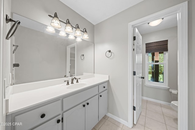 bathroom featuring toilet, tile patterned floors, baseboards, and vanity