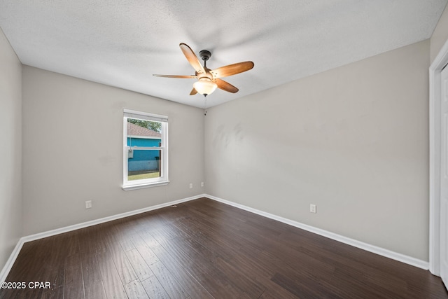 spare room featuring baseboards, a ceiling fan, dark wood finished floors, and a textured ceiling