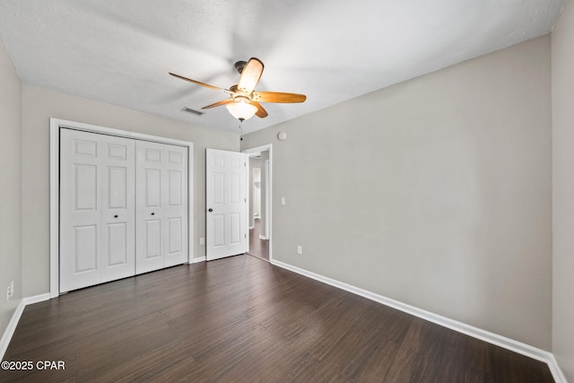 unfurnished bedroom with a ceiling fan, visible vents, baseboards, a closet, and dark wood-style floors