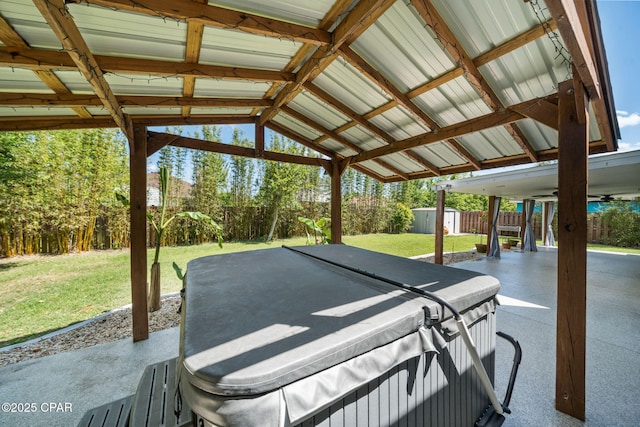 view of patio featuring a storage shed, an outdoor structure, a hot tub, and a fenced backyard