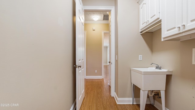1222 Huntington Ridge Rd, Lynn Haven, FL 32444 - laundry area featuring visible vents, ornamental molding, baseboards, cabinet space, and light wood-style flooring
