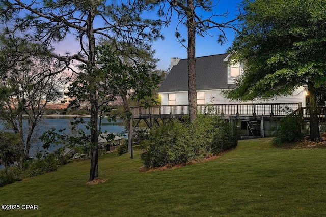 yard at dusk with a deck with water view