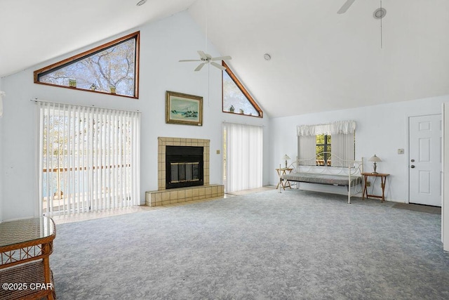 living room with a ceiling fan, carpet, high vaulted ceiling, and a tile fireplace