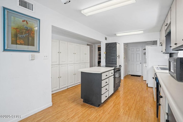 kitchen with visible vents, light countertops, white cabinetry, light wood-style flooring, and black appliances