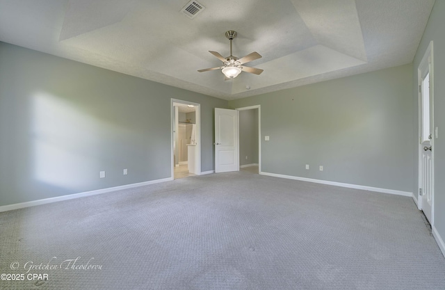unfurnished bedroom featuring light colored carpet, baseboards, visible vents, and a raised ceiling