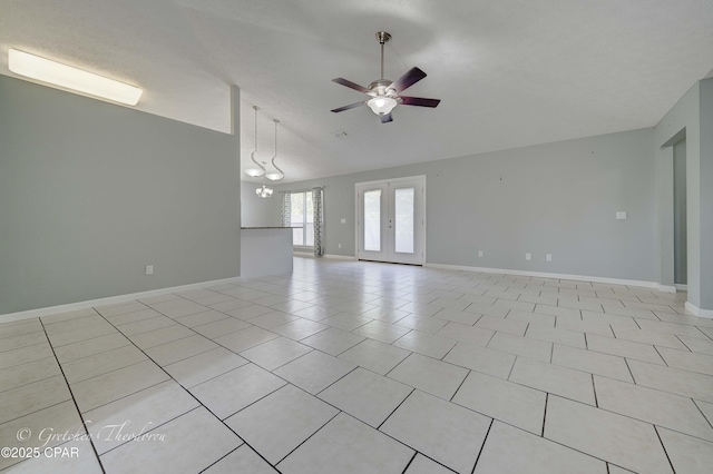 empty room featuring baseboards, ceiling fan with notable chandelier, light tile patterned flooring, and lofted ceiling