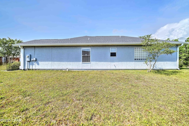 back of property featuring stucco siding and a yard
