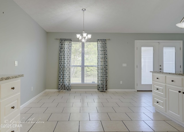 unfurnished dining area featuring light tile patterned floors, baseboards, and a notable chandelier
