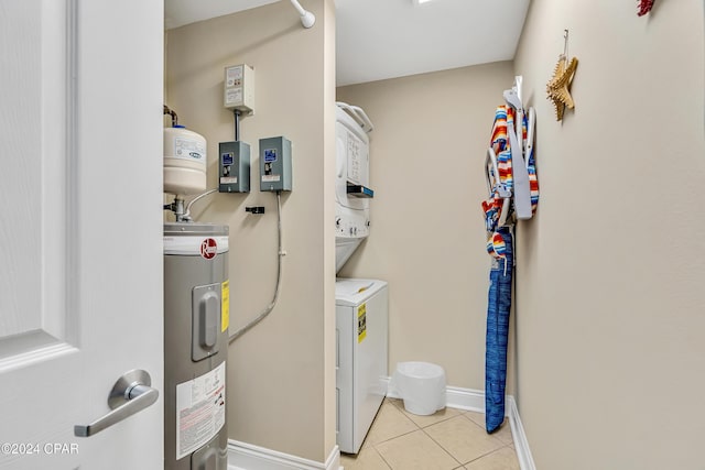 laundry room featuring laundry area, baseboards, water heater, stacked washer and clothes dryer, and light tile patterned flooring