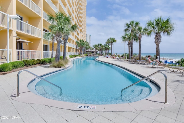 community pool with a water view and a patio area