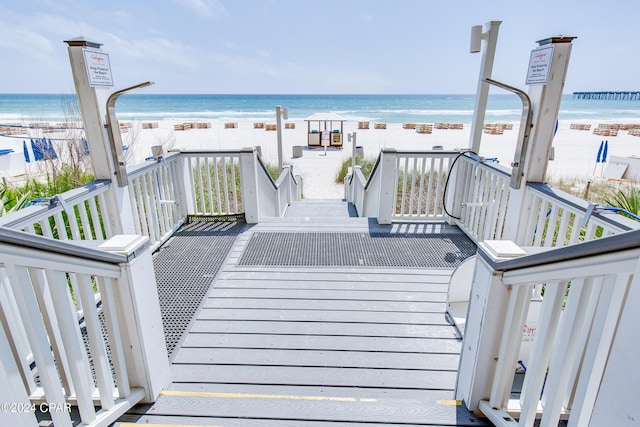 wooden deck featuring a view of the beach and a water view