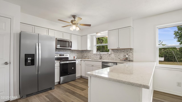 325 Bell Cir, Lynn Haven, FL 32444 - kitchen with appliances with stainless steel finishes, a sink, a peninsula, dark wood-style flooring, and decorative backsplash