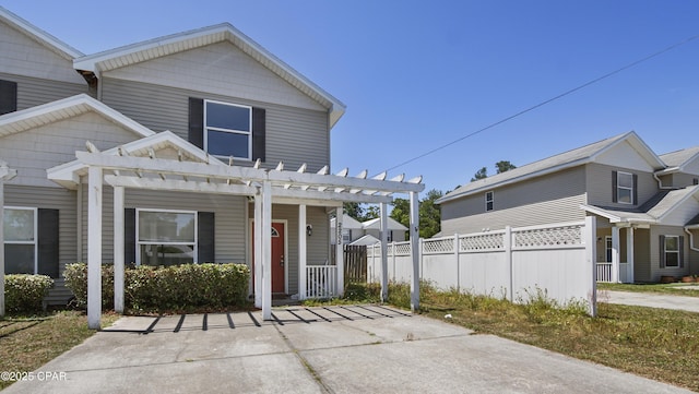 view of front facade with fence, a pergola, and covered porch