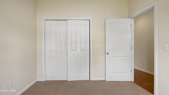unfurnished bedroom with baseboards, carpet, and a closet