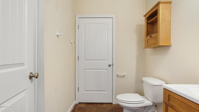 half bath featuring toilet, baseboards, and vanity