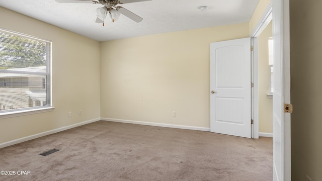carpeted empty room featuring baseboards, ceiling fan, and visible vents
