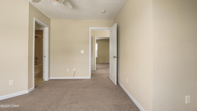 unfurnished bedroom with carpet floors, a textured ceiling, ceiling fan, and baseboards