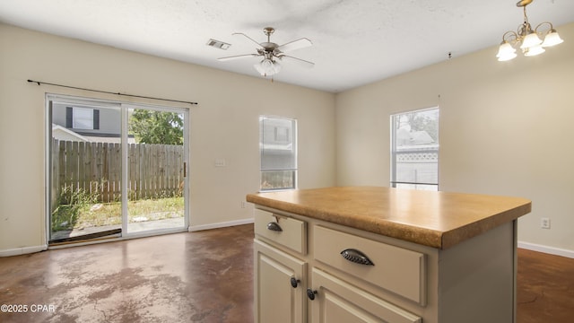 kitchen featuring visible vents, a kitchen island, baseboards, finished concrete floors, and ceiling fan with notable chandelier