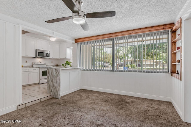 kitchen with white range with electric cooktop, stainless steel microwave, light colored carpet, and plenty of natural light