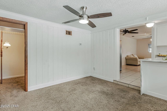 unfurnished living room with light carpet, a ceiling fan, a textured ceiling, and visible vents