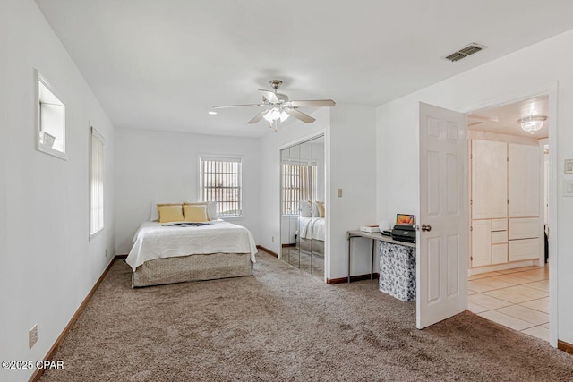 bedroom with visible vents, a closet, light carpet, baseboards, and ceiling fan