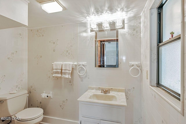 bathroom with toilet, tile walls, and vanity