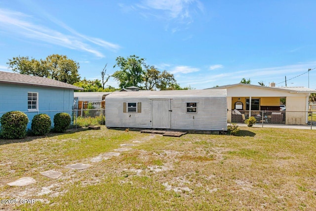 back of property featuring a lawn, an outdoor structure, and a fenced backyard