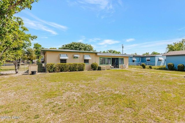 view of front of home with fence, central AC unit, and a front lawn