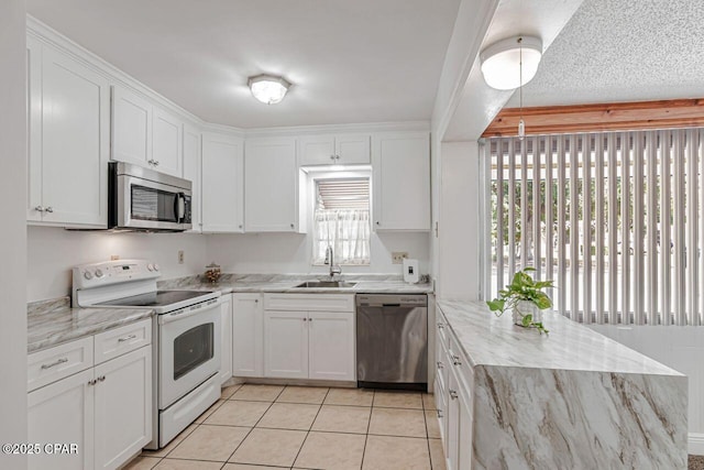 kitchen with light stone countertops, a sink, light tile patterned floors, white cabinets, and stainless steel appliances