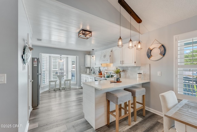 135 Bid A Wee Ln, Panama City Beach, FL 32413 - kitchen featuring a sink, white appliances, light wood-style flooring, backsplash, and white cabinets