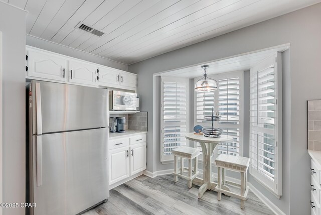 135 Bid A Wee Ln, Panama City Beach, FL 32413 - kitchen with freestanding refrigerator, white microwave, healthy amount of natural light, white cabinetry, and wooden ceiling