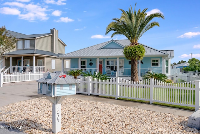 135 Bid A Wee Ln, Panama City Beach, FL 32413 - view of front facade with a porch, a fenced front yard, metal roof, and a chimney