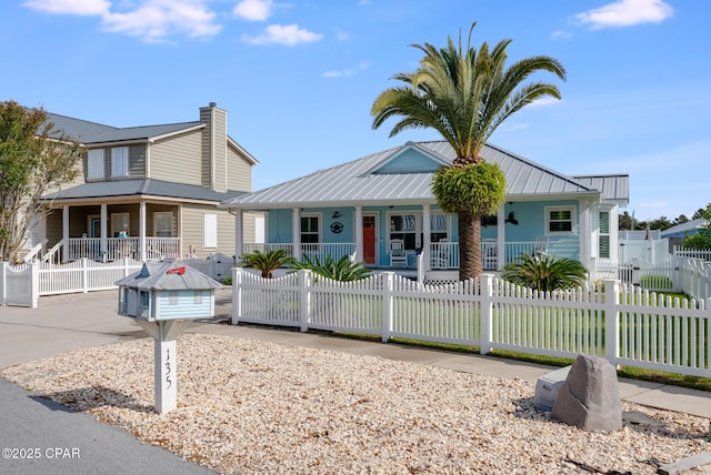 view of front of home with a porch, a fenced front yard, metal roof, and a gate