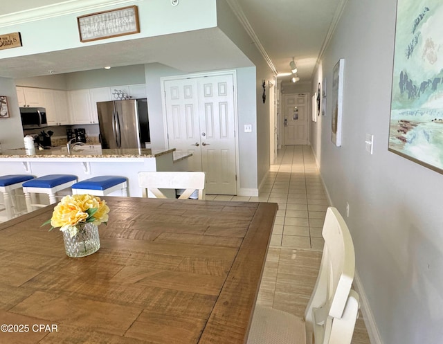 dining space with crown molding, baseboards, and light tile patterned flooring