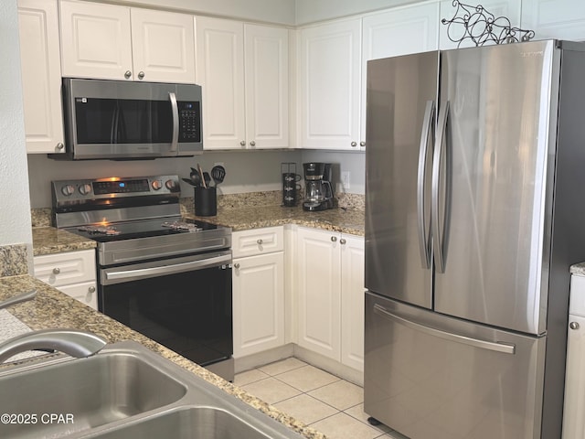 kitchen featuring white cabinets, stainless steel appliances, a sink, and light tile patterned floors