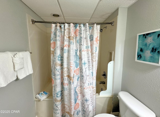 full bath with toilet, a paneled ceiling, and shower / tub combo with curtain