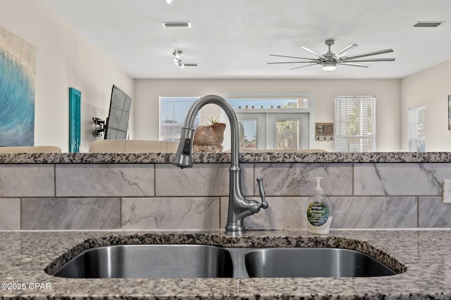 interior details with ceiling fan, stone countertops, a sink, and visible vents