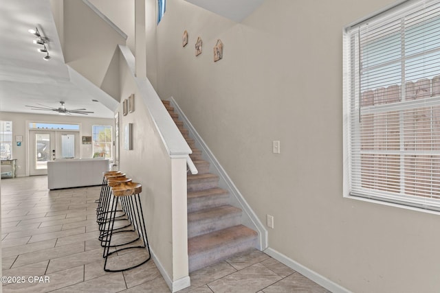 stairs featuring tile patterned flooring, a ceiling fan, and baseboards