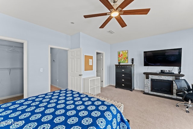 carpeted bedroom with ceiling fan, a fireplace, baseboards, visible vents, and a closet