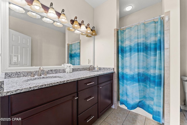 bathroom with a sink, tile patterned floors, toilet, and double vanity