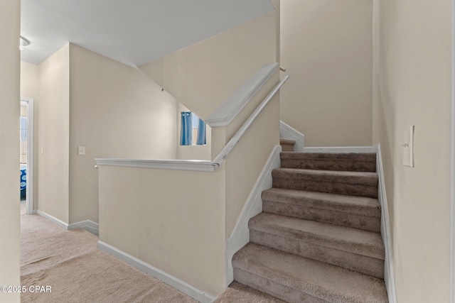 stairway featuring baseboards and carpet flooring
