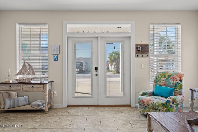 doorway featuring french doors, baseboards, light tile patterned floors, and a healthy amount of sunlight