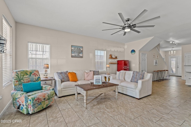 living area featuring ceiling fan with notable chandelier