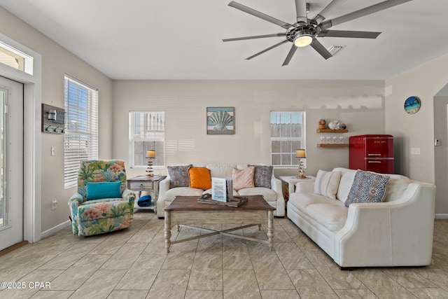 living room with visible vents, a ceiling fan, and baseboards