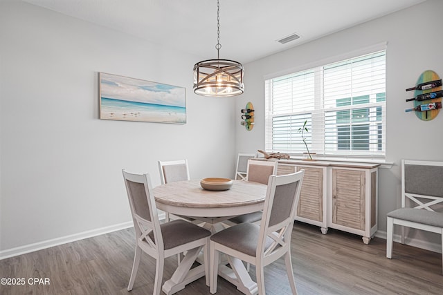 dining area with light wood-style floors, baseboards, visible vents, and a notable chandelier