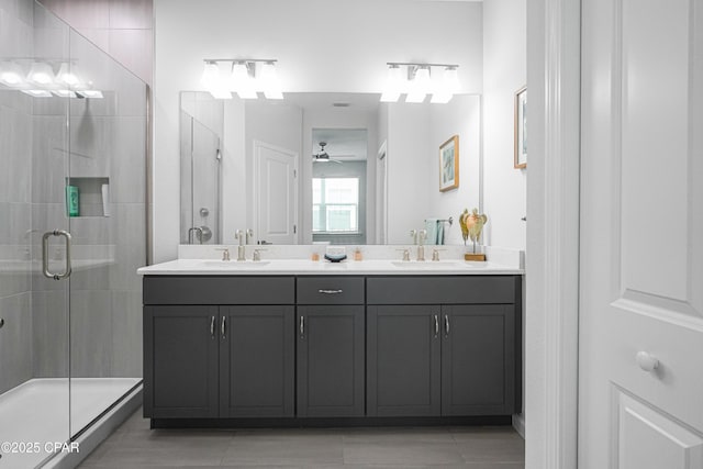 bathroom featuring double vanity, ceiling fan, a shower stall, and a sink