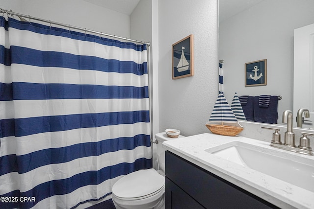 bathroom featuring vanity, a textured wall, a shower with curtain, and toilet